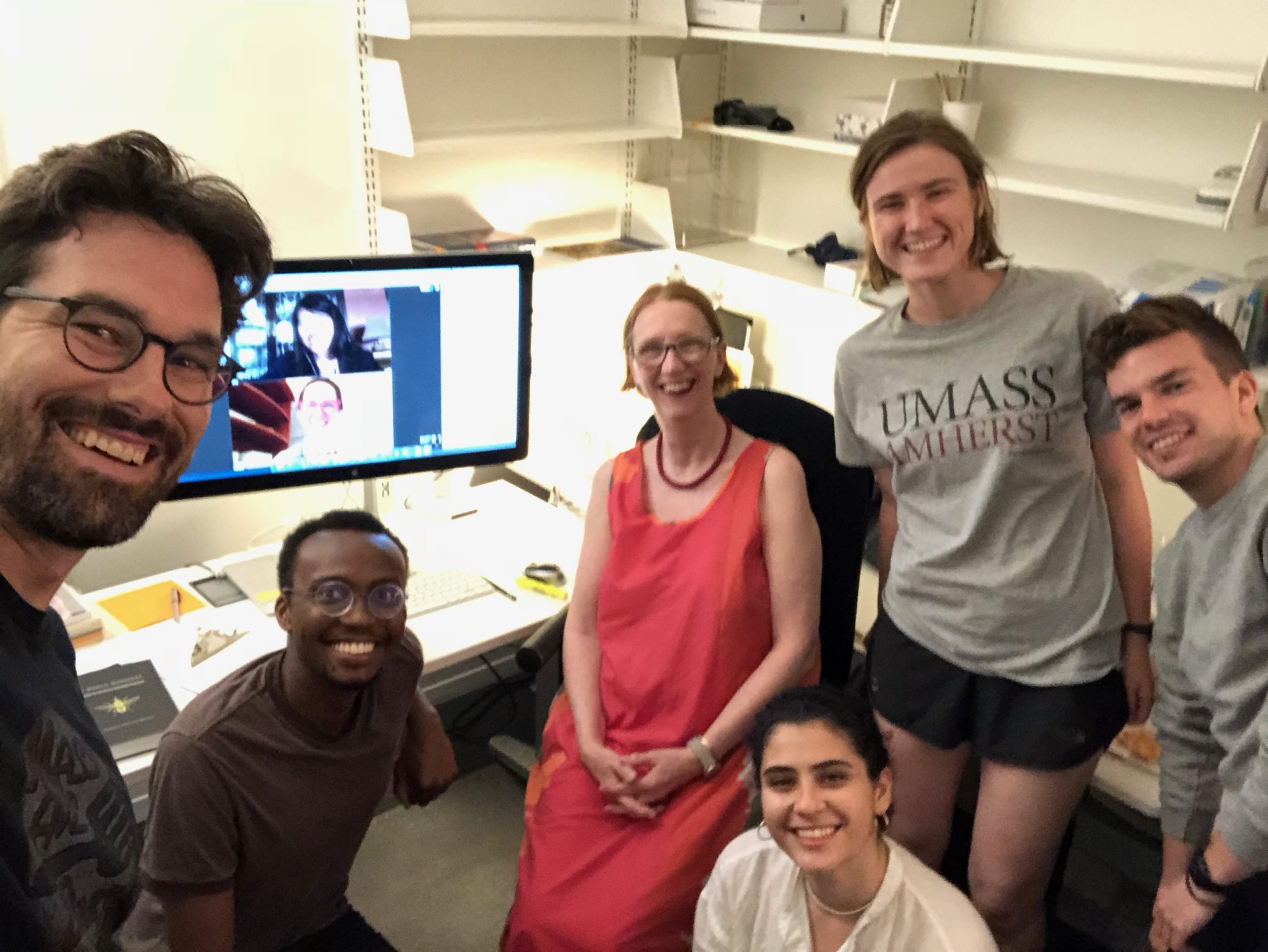 A selfie of the Responsive Science Working Group sitting in an office, with some of the members physically present and others on a computer screen in the background